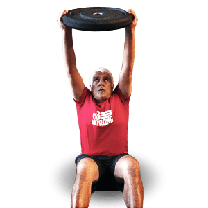 Middle age man lifting a heavy plate while wearing a red 3Strong Fitness t-shirt
